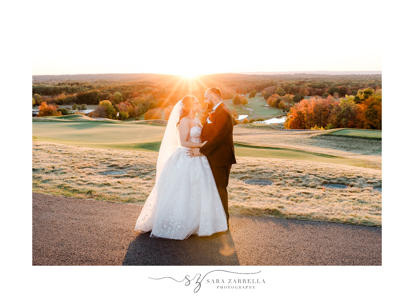 bride and groom stand on driveway with setting sun behind them