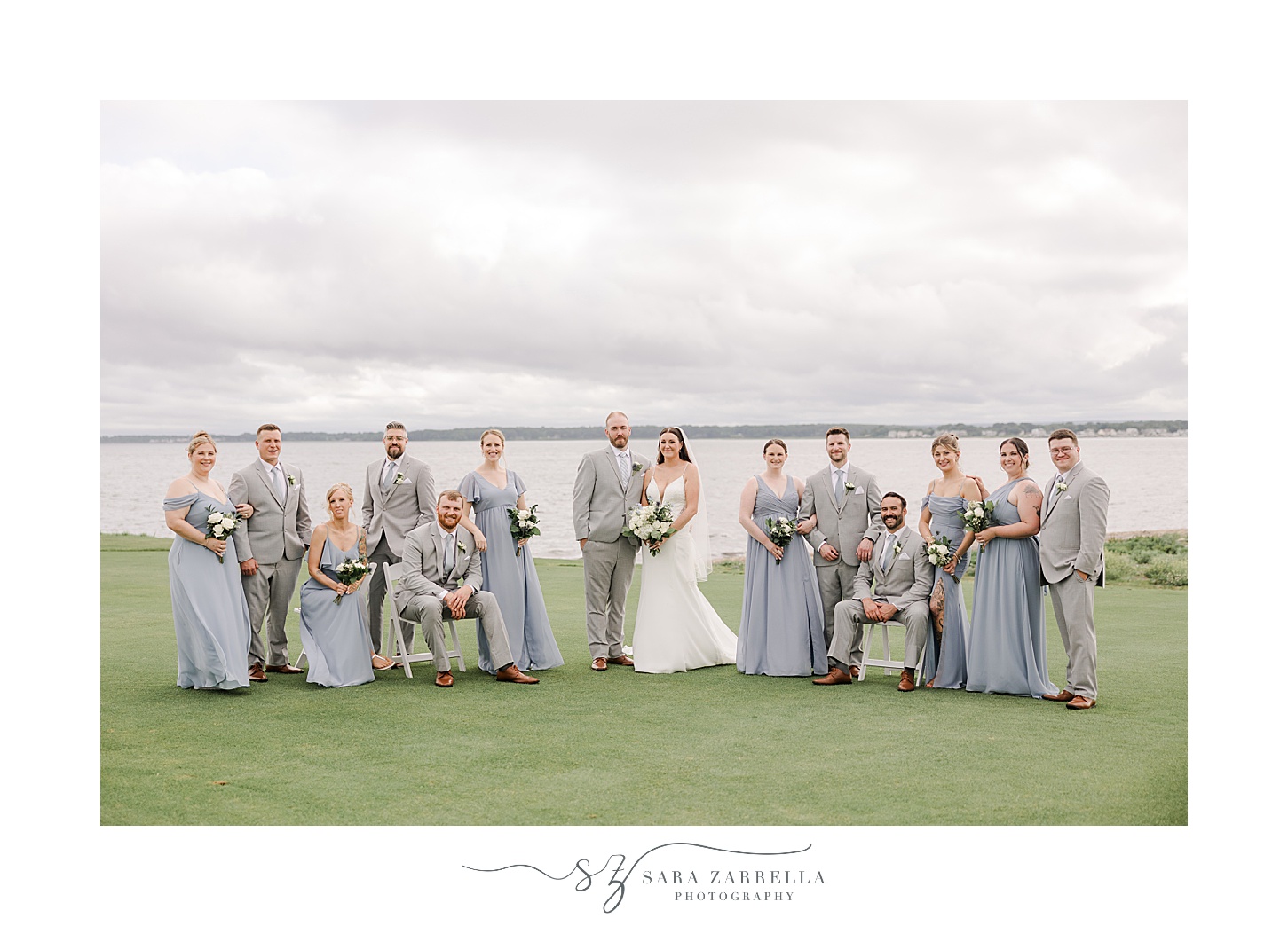 bride and groom stand on lawn with wedding party around them in light blue and grey attire